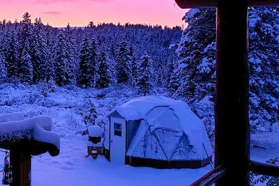 15 foot diameter geodesic greenhouse under a blanket of snow with a vibrant pink and purple sunset