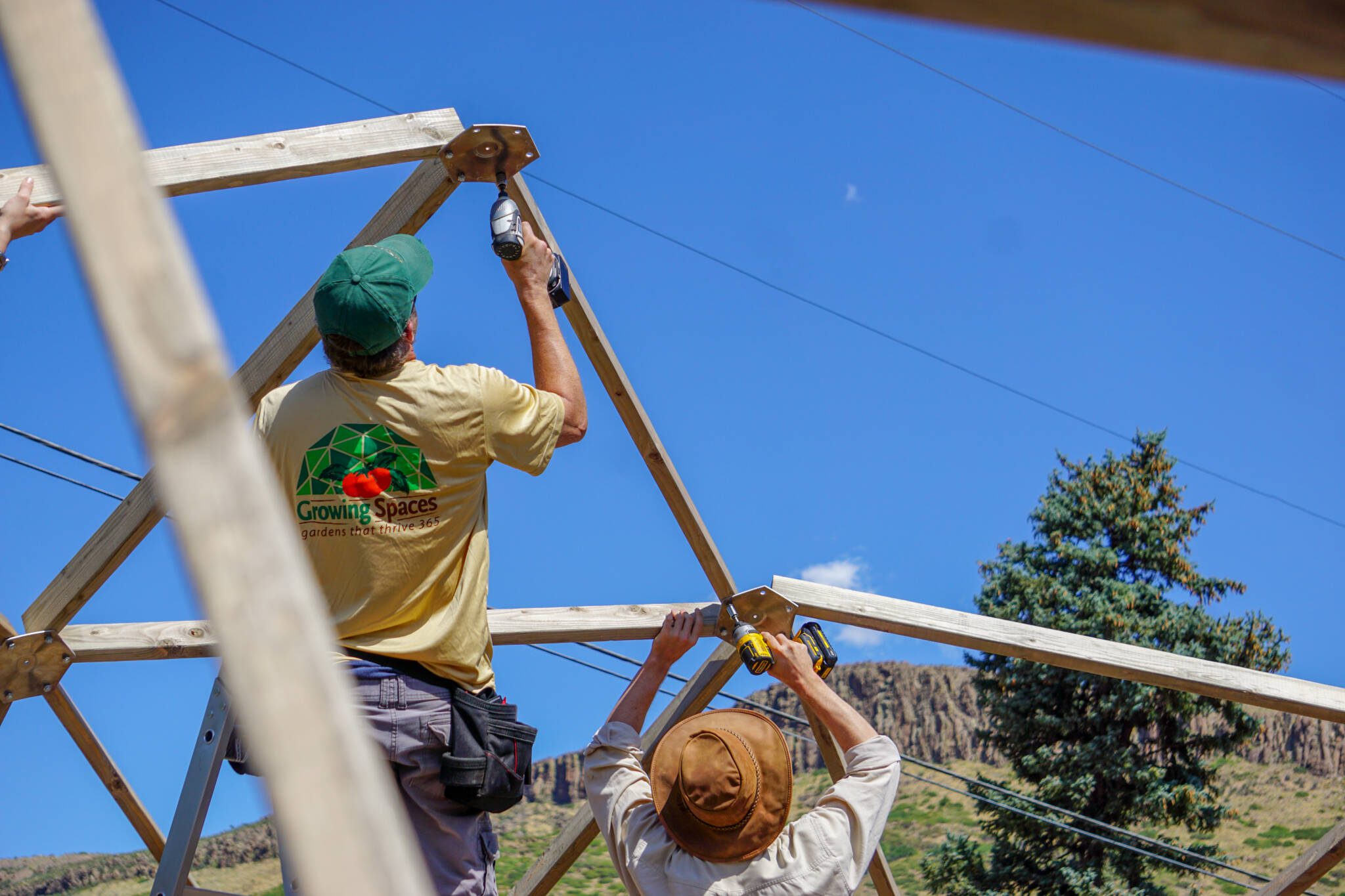 Two installers fastening the wooden frame of a Growing Dome