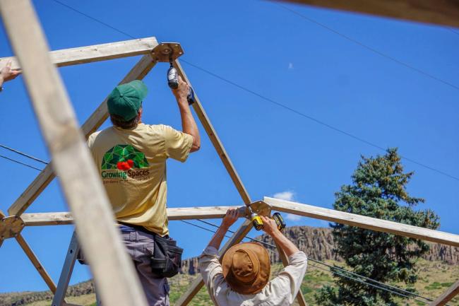 Two installers fastening the wooden frame of a Growing Dome