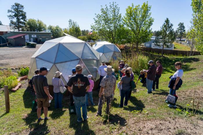 Group of people standing outside two growing dome geodesic greenhouses