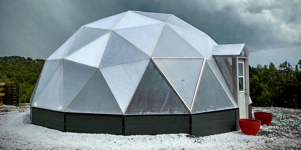 22 foot growing dome with hail on ground surrounding dome and dark grey skies behind