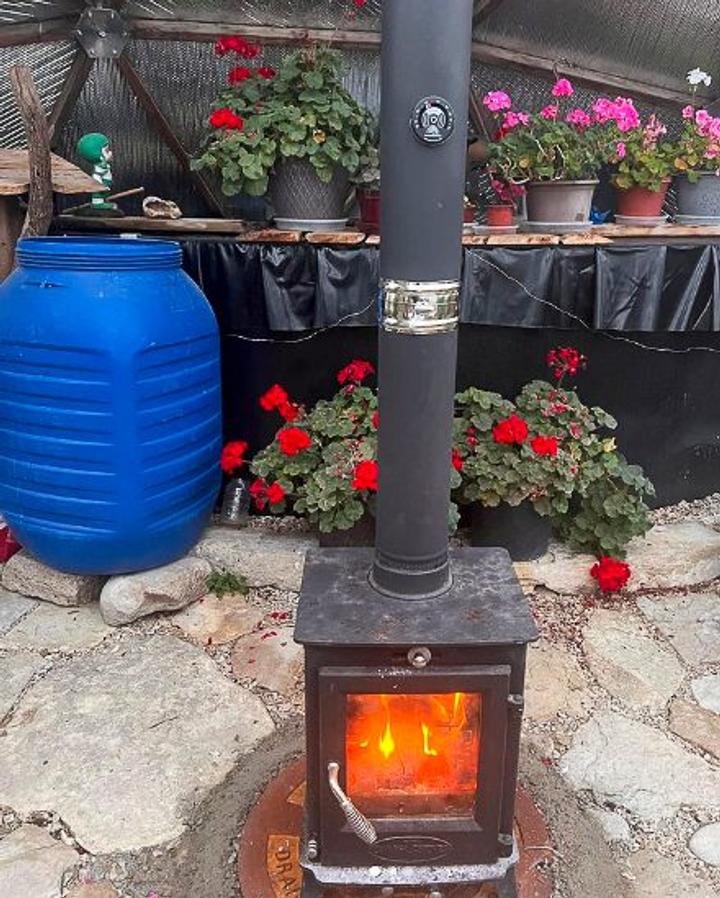 Small wood stove with fire lit inside a 22' Growing Dome