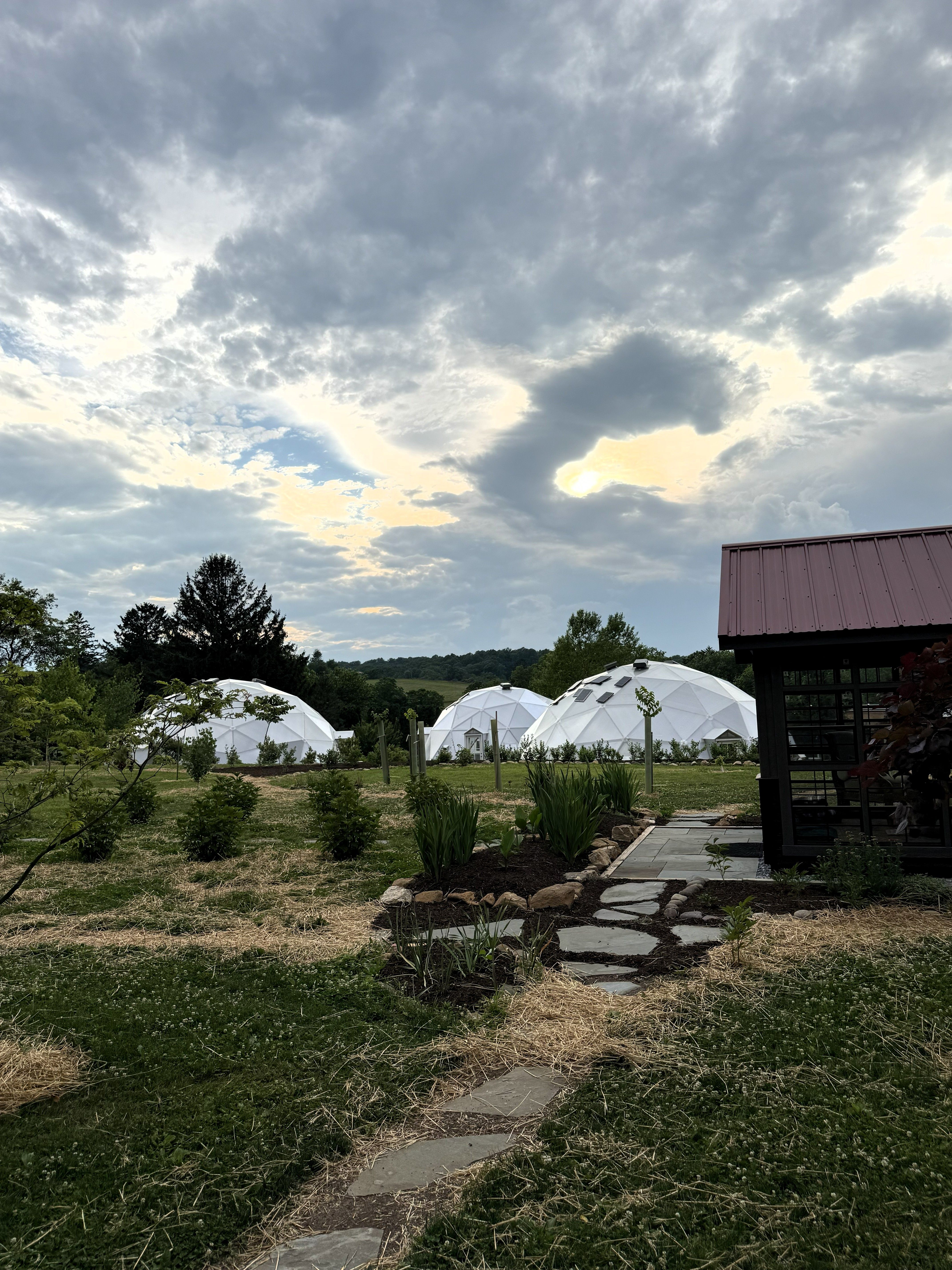 Three domes at Kula Kamala in the background as stone path leads to a building in foreground