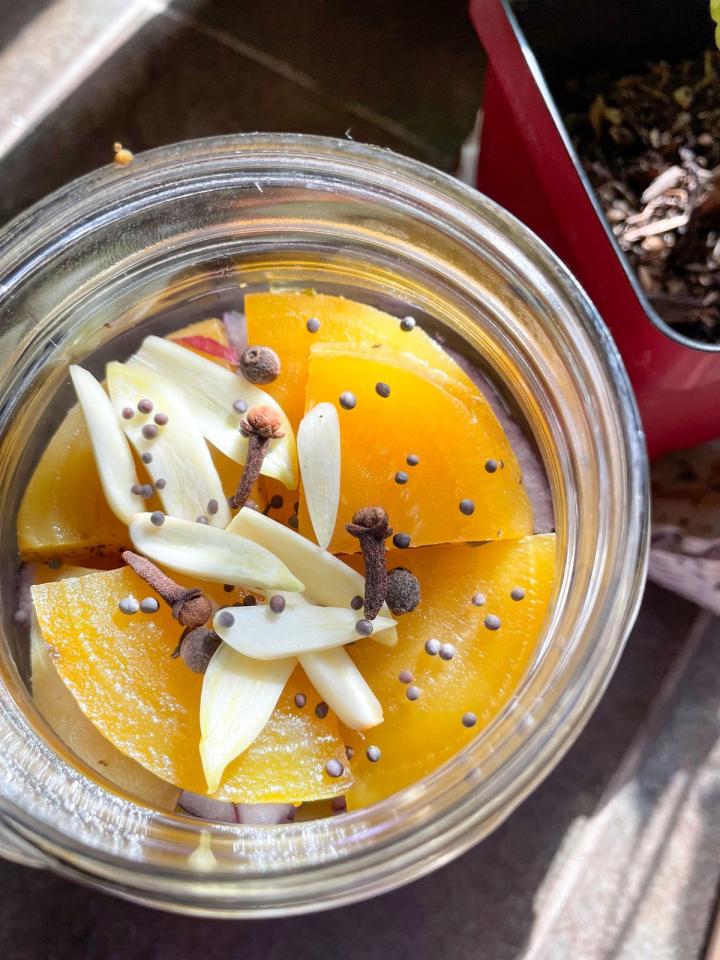 looking down at beets in a jar with garlic and spices sprinkled on top