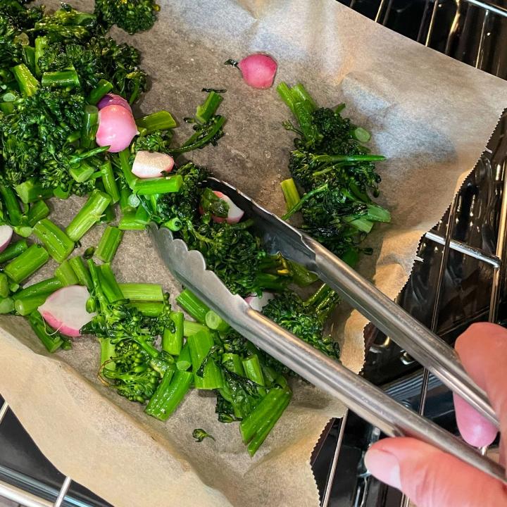 tossing roasted veggies on a sheet pan in the oven for the pesto pasta salad