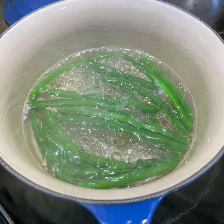 green beans being blanched in boiling water in a pot