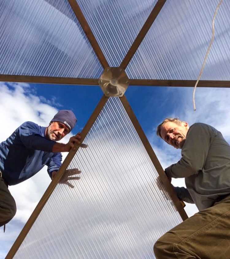 two men installing polycarbonate panels in greenhouse frame