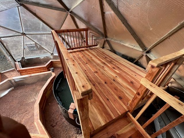 Custom greenhouse interior deck above a pond with railings