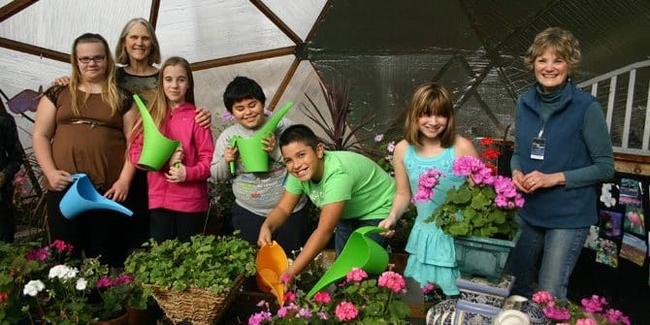 kids watering flowers in an Oregon school Growing Dome
