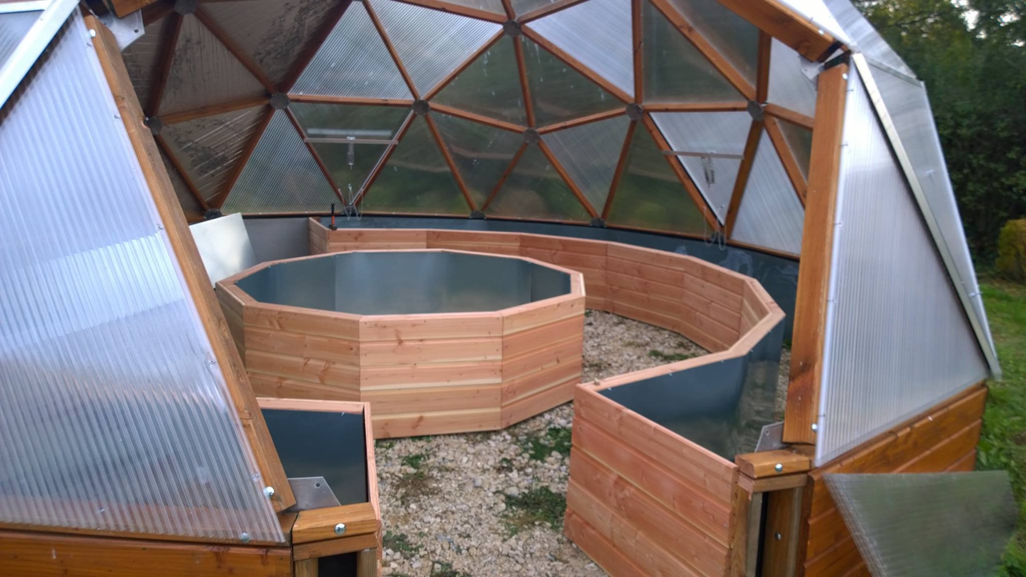 looking inside of the growing dome greenhouse before the doorway has been installed shows a center bed and perimeter beds