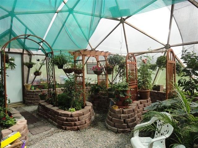 inside a greenhouse with trellises and stone pavers used for the raised beds