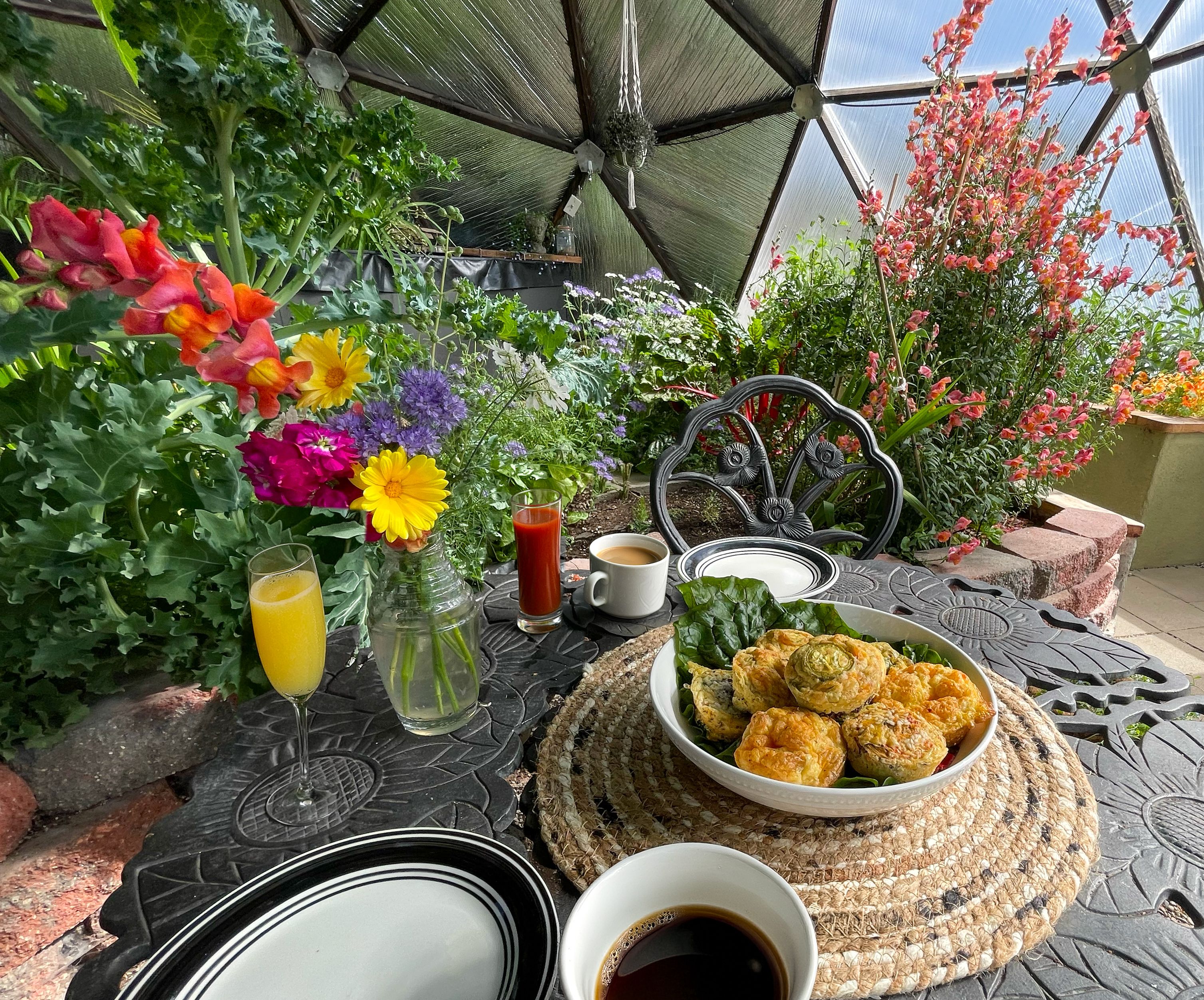 egg bites on a platter on a metal table in a dome greenhouse with lots of plants and flowers growing