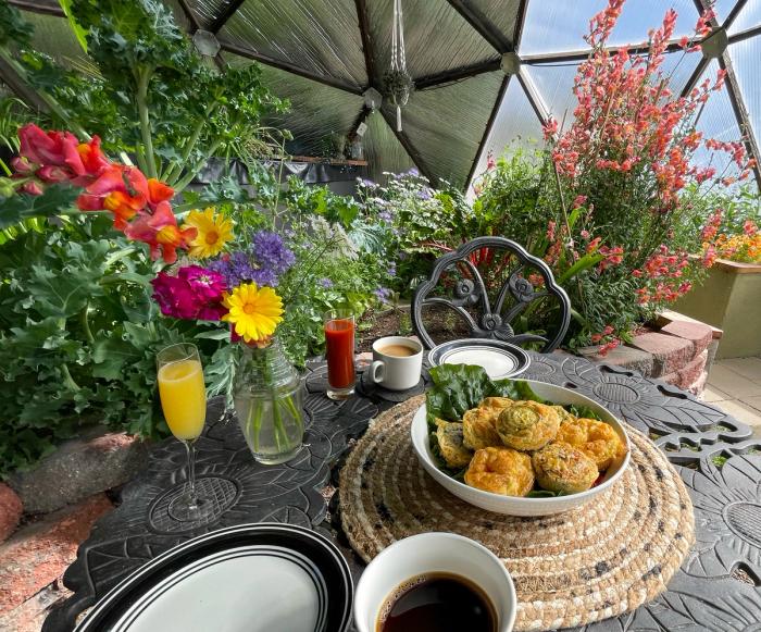 egg bites on a platter on a metal table in a dome greenhouse with lots of plants and flowers growing