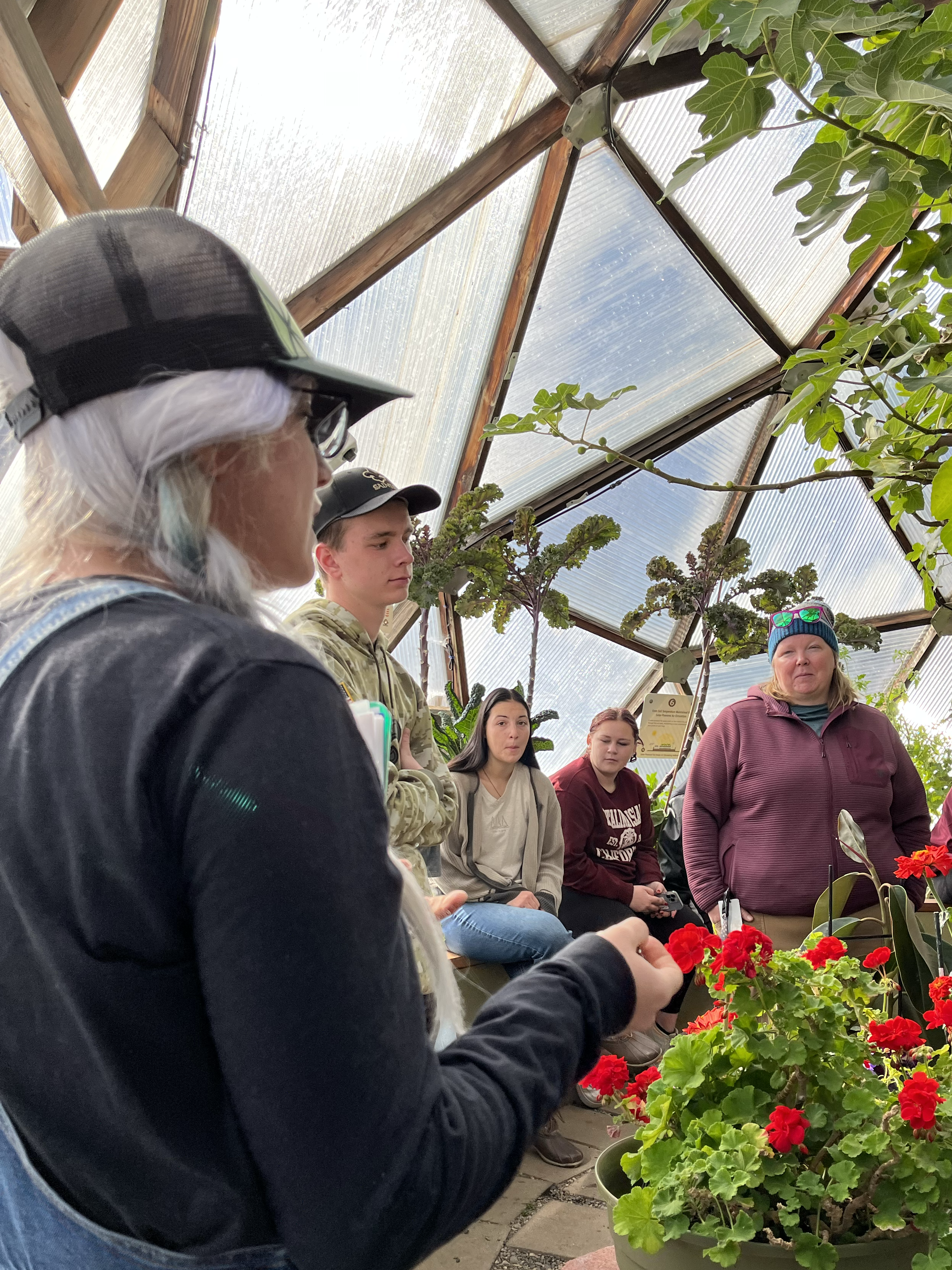 students and teacher learning more about gardening in the growing dome greenhouses