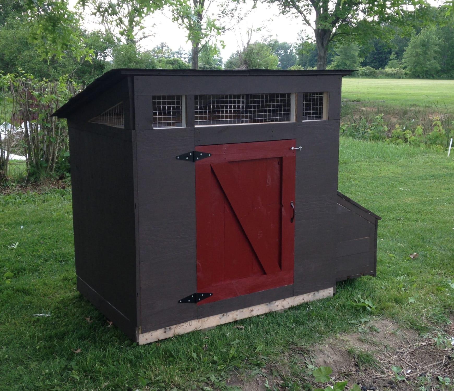 Chicken coop made from OSB painted charcoal gray with a red door