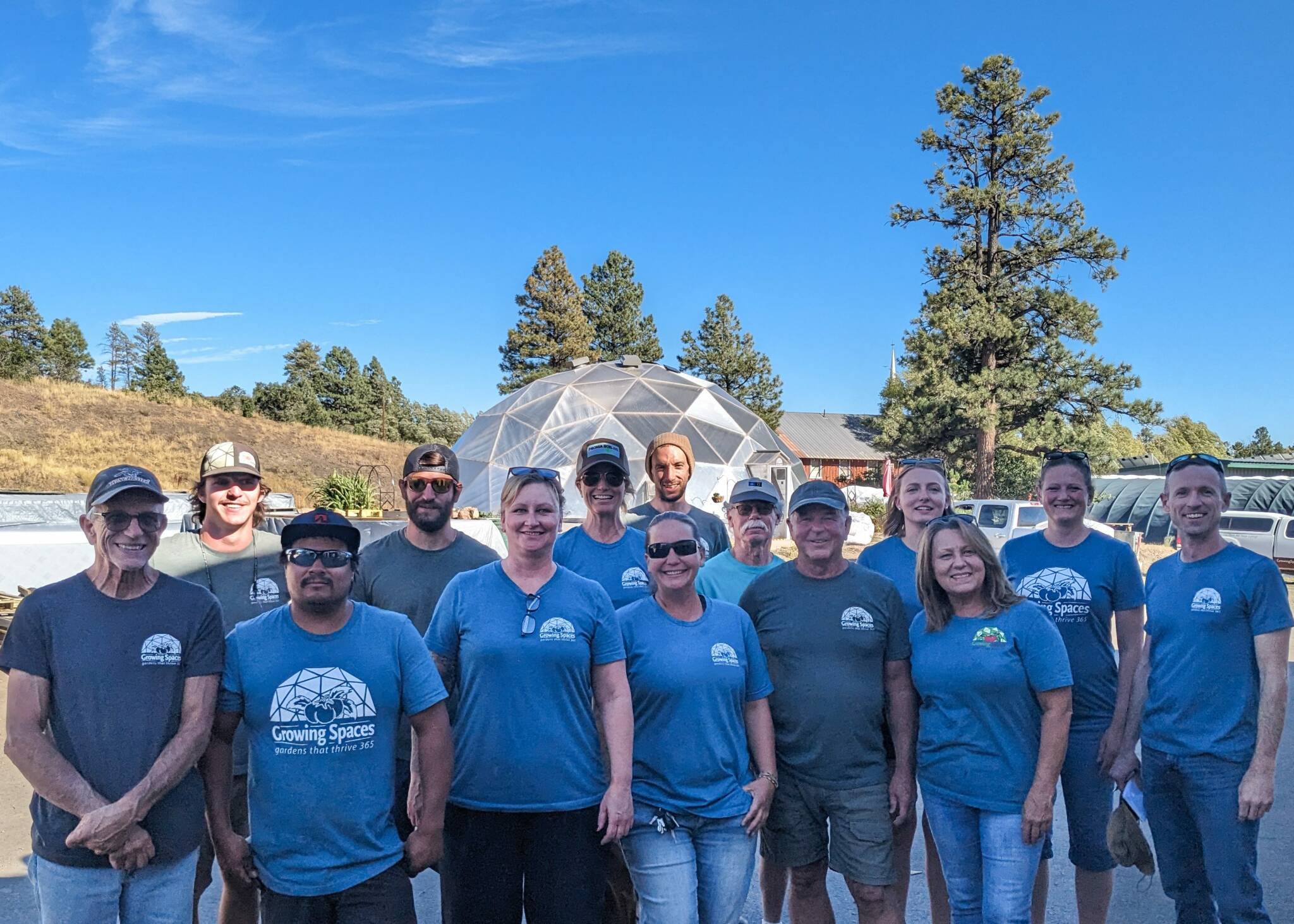team members of Growing Spaces gathered for a portrait with one of the Growing Dome greenhouses in the background