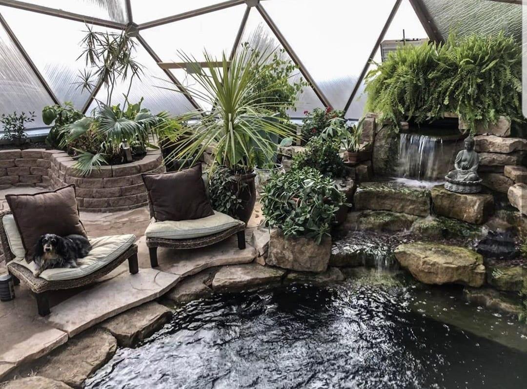 sunken pond with a waterfall and seating area inside the greenhouse