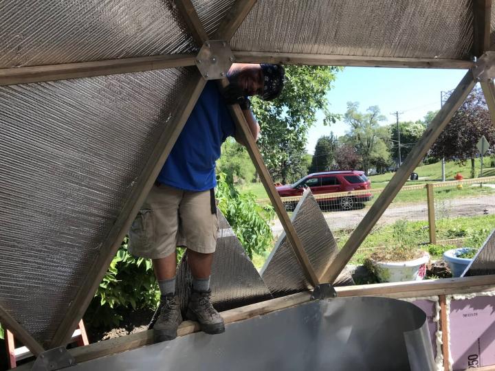 Volunteer installing polycarbonate panels with reflective insulation