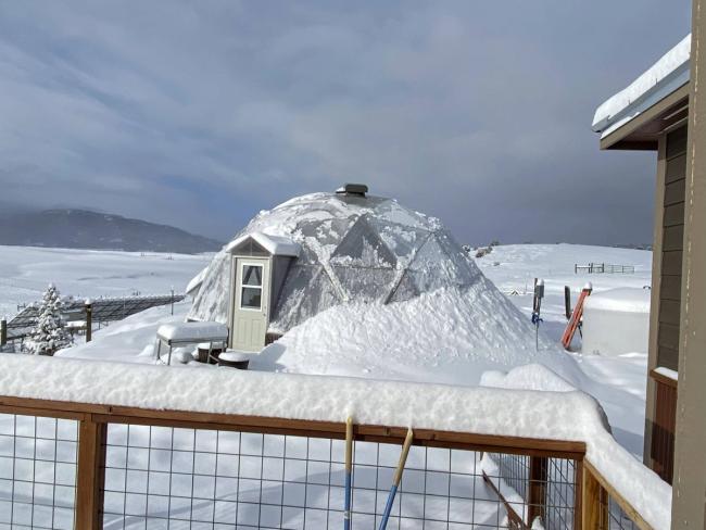 Growing Dome greenhouse surrounded by snow with a light dusting on the polycarbonate panels