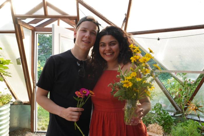 Couple holding fresh-picked flowers in a Growing Dome greenhouse during a garden fundraiser