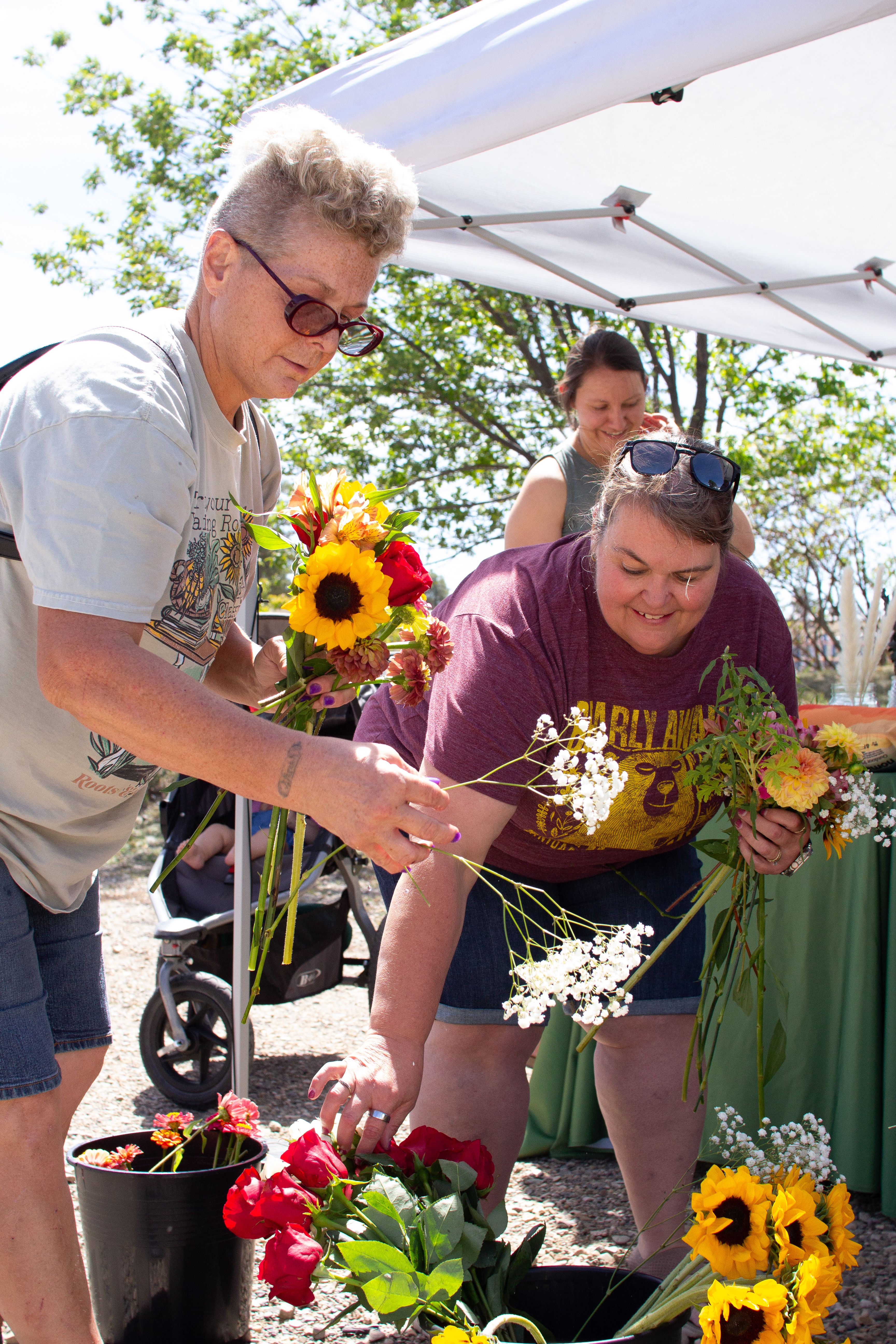 Three women smiling selecting flowers for bouquets