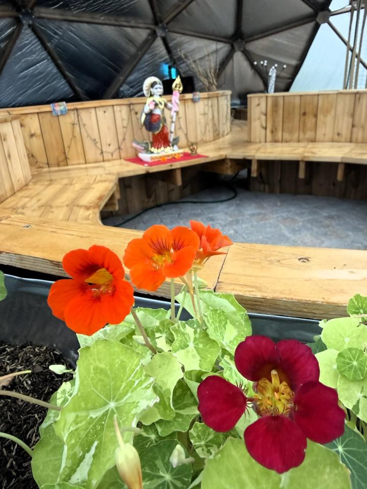Kula Kamala dome with nasturiums in the foreground and closer look at statue sitting in the middle of a large bench seating area