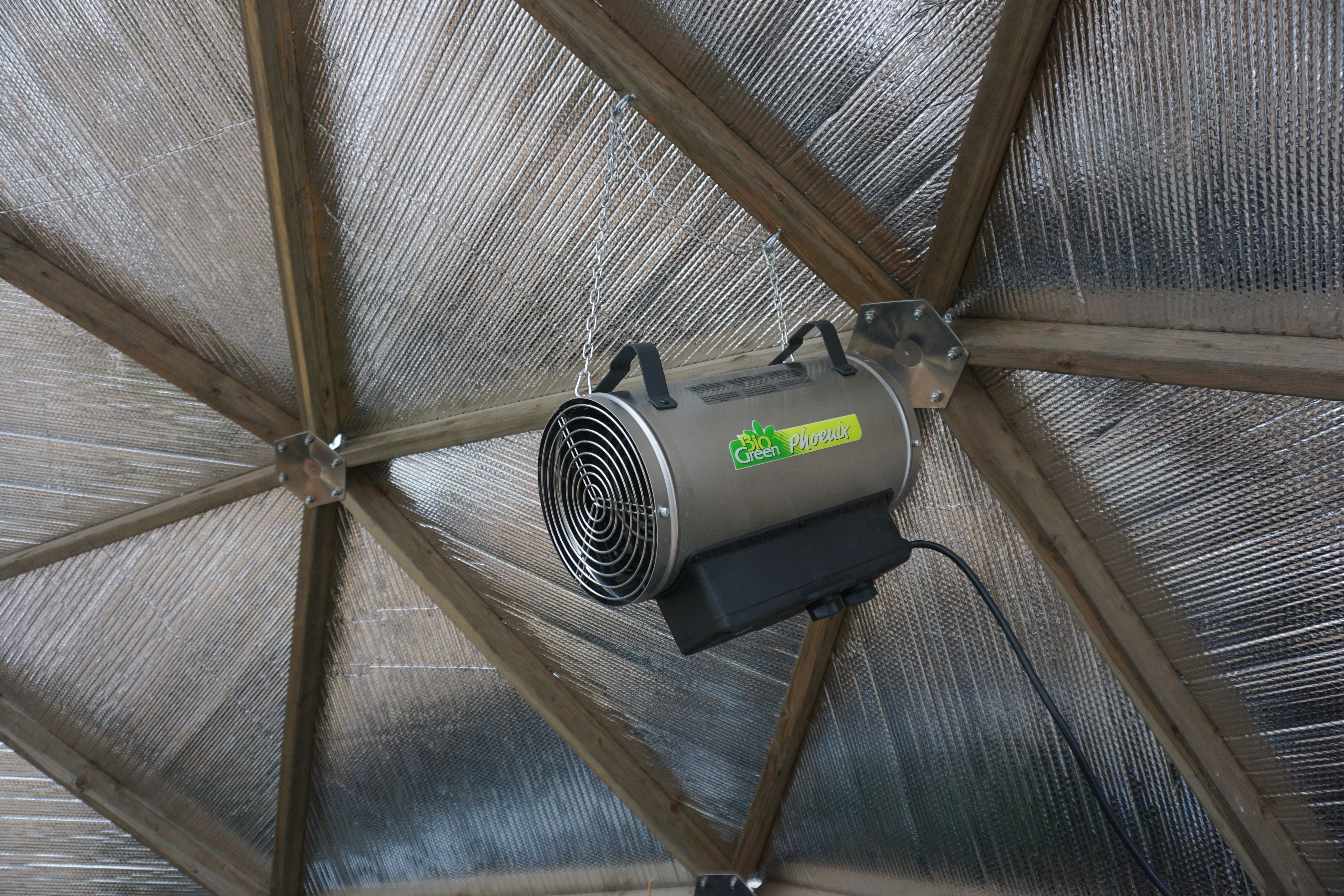 Electric greenhouse heater hanging from wooden strut