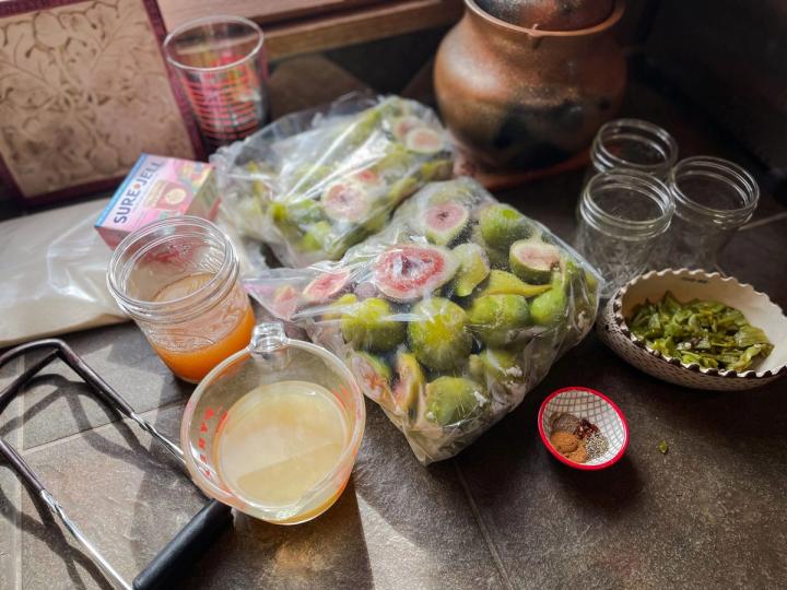 fig jam ingredients frozen figs chopped green chiles vinegar apple juice lime juice spices pectin jar lifter and glass jars sitting on a countertop