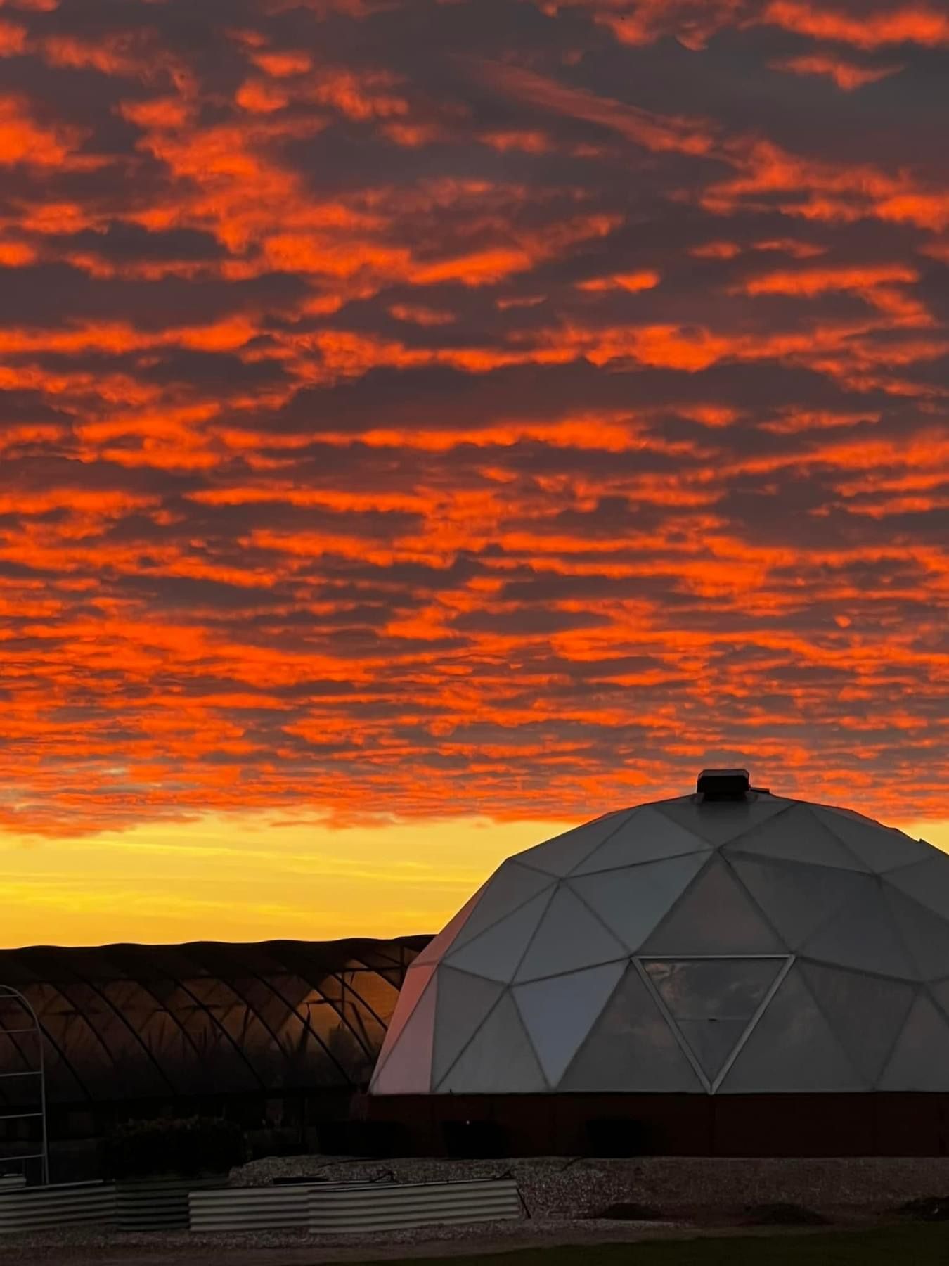 Bright red orange clouds behind a Growing Dome at sunset