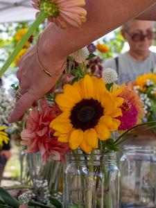 Close up of a sunflower in a bouquet with people in the background
