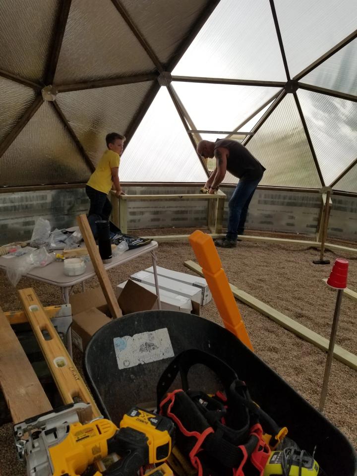 friends helping build Probst dome constructing raised beds inside the greenhouse