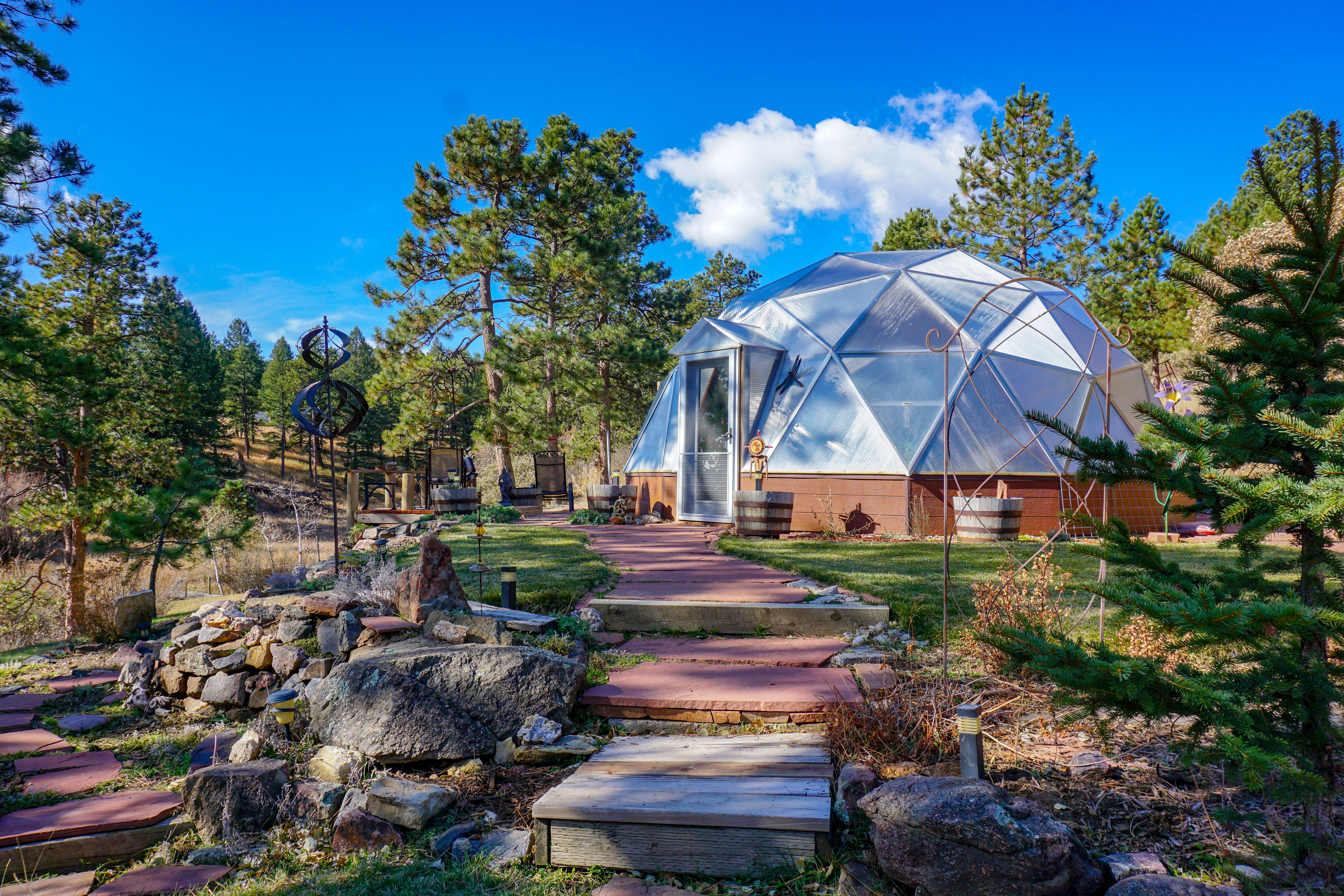 growing dome greenhouse with beautiful landscaped pathways leading to it in a pine forest
