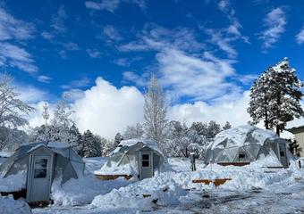 Three Growing Dome Greenhouses covered with snow and blue sky in background