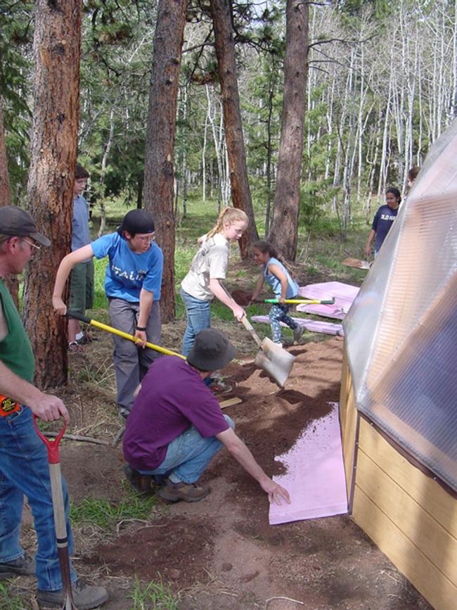 people installing insulation around the perimeter of the greenhouse