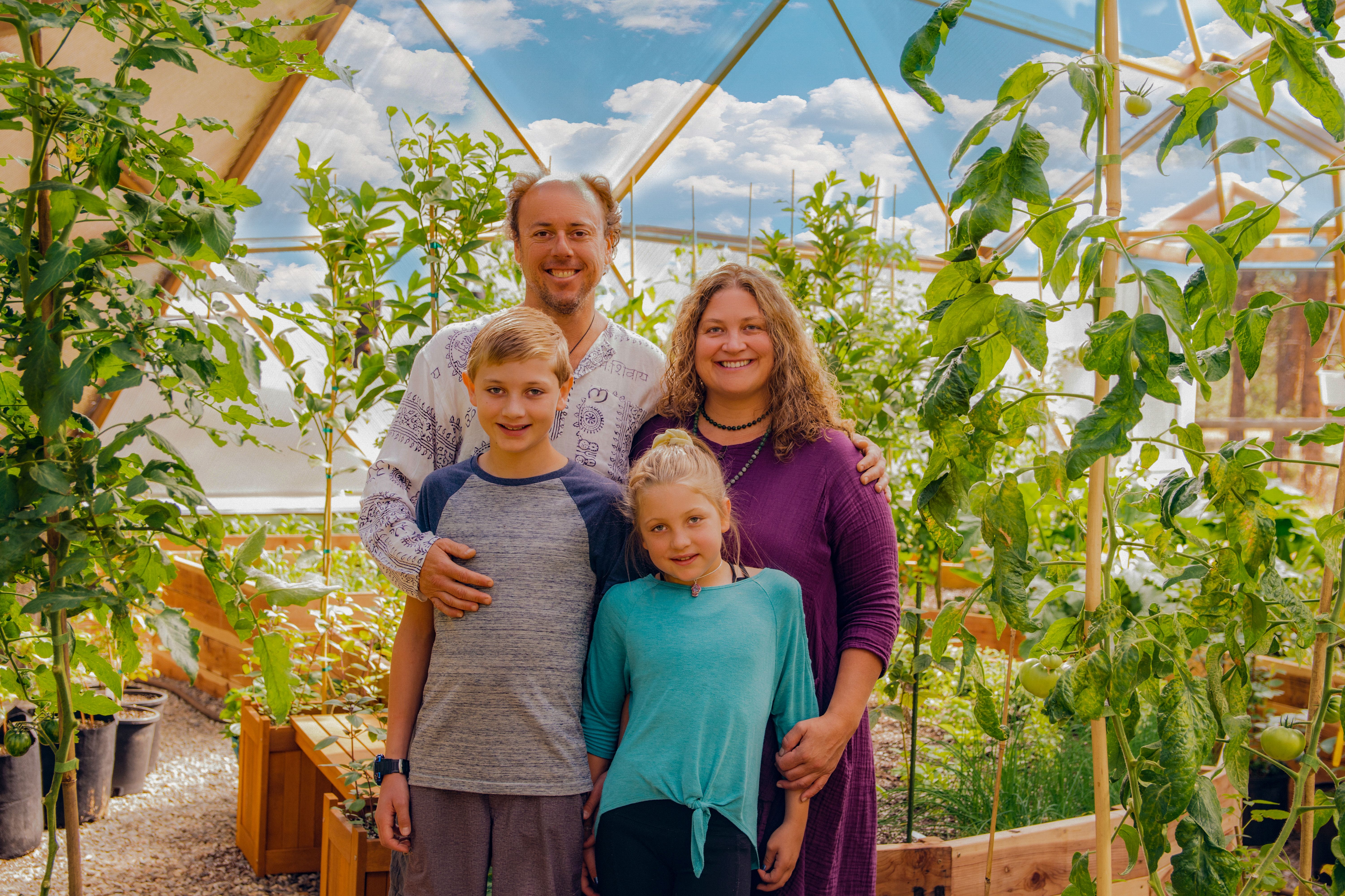 Man, woman, and two children posing for a photo inside a Growing Dome greenhouse