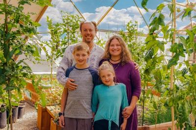 Man, woman, and two children posing for a photo inside a Growing Dome greenhouse