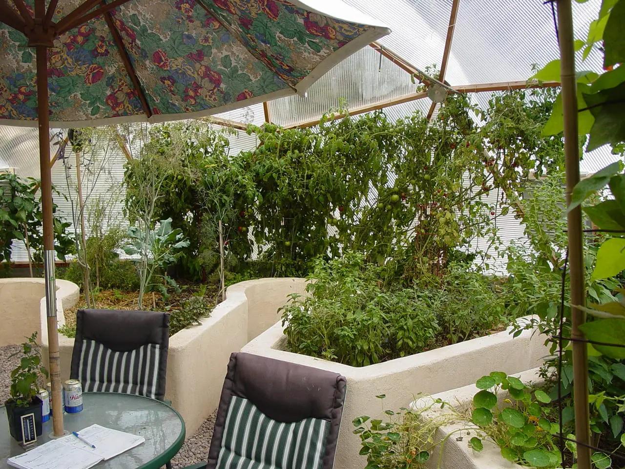 seating area with an umbrella and raised beds finished with stucco inside the greenhouse
