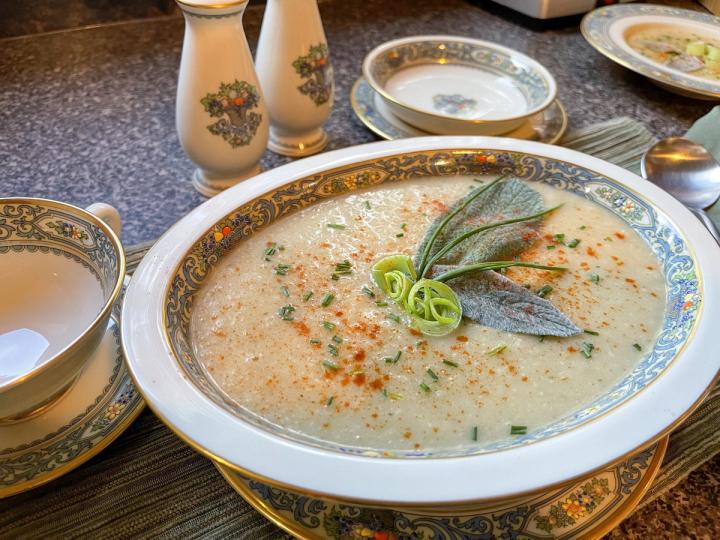Celeriac Soup on a table Garnished with Sage, Leek, Chives, and Smoked Paprika