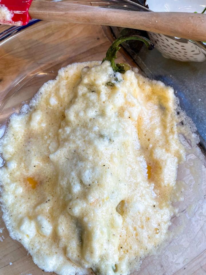 stuffed chile laid in the bowl of batter