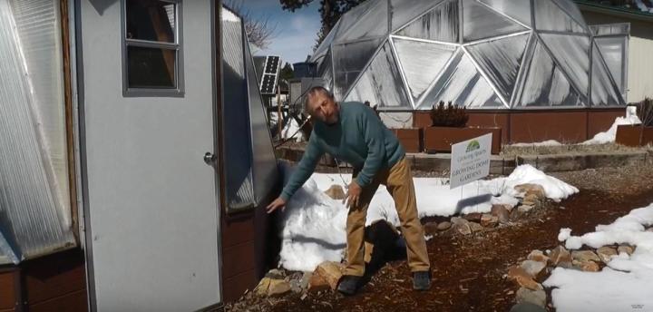Man pointing to the insulated foundation wall on a growing dome during winter
