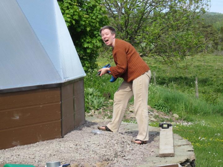 Growing Dome Greenhouse owner installing trim strips in Sweden