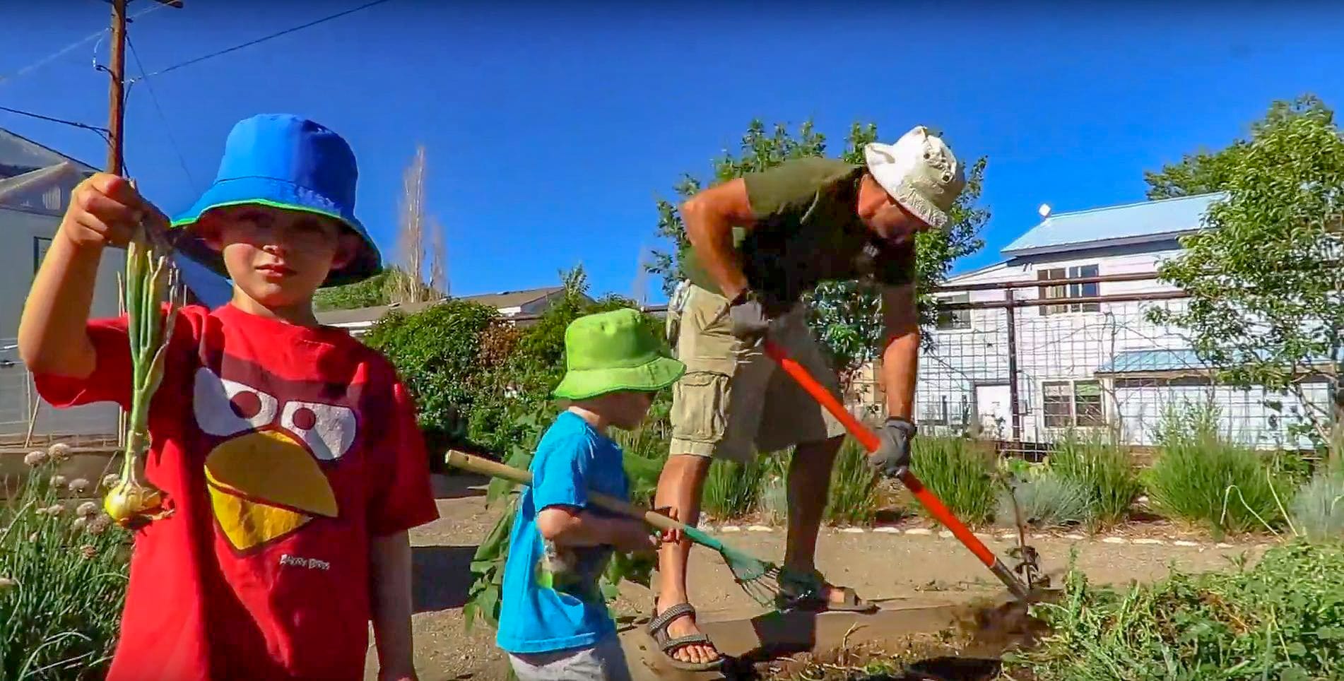 Andrew and his sons working in the community garden next to the greenhouse