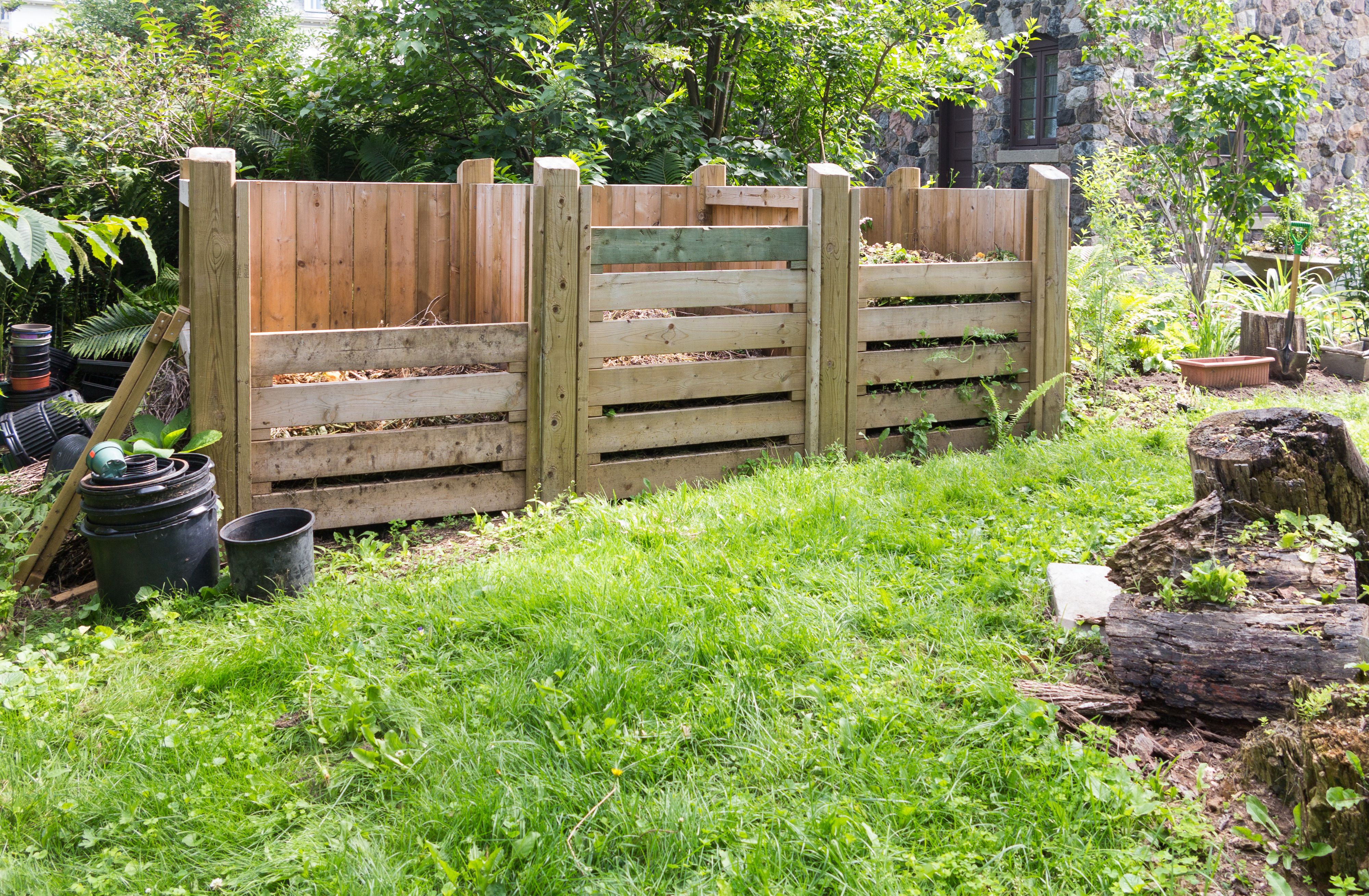 Three wooden compost bins outdoors in a garden