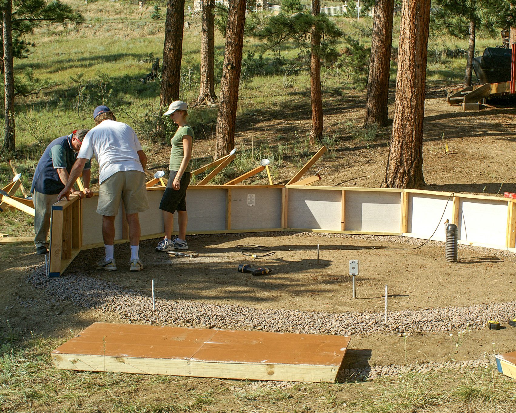 people erecting greenhouse foundation wall on top of a gravel ring