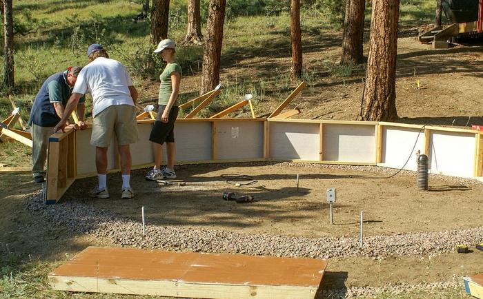 people erecting greenhouse foundation wall on top of a gravel ring