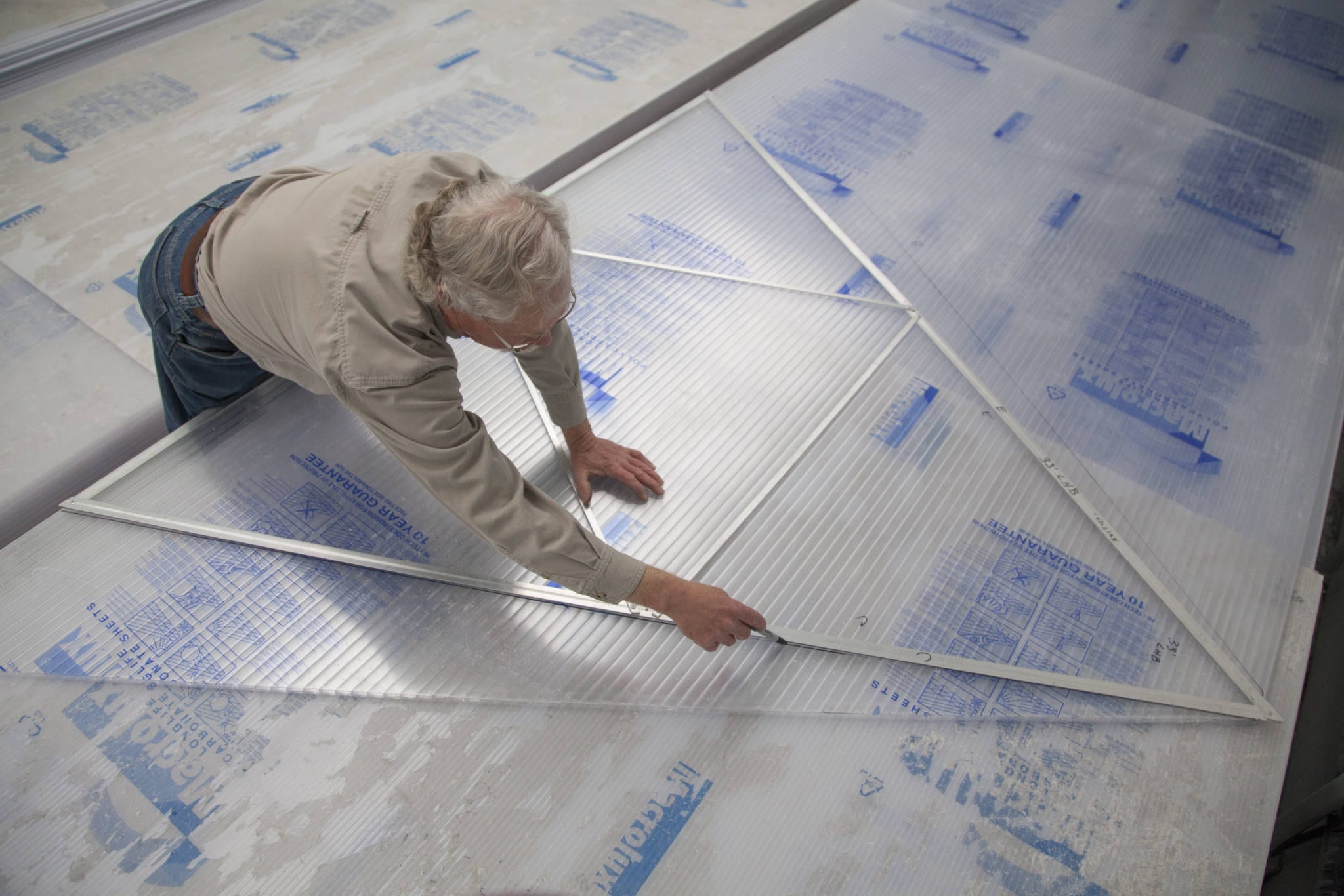 person using a jig to mark and cut polycarbonate glazing