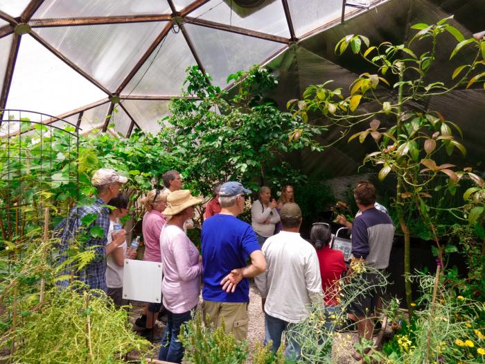 Group of people gathered inside a Growing Dome greenhouse listening to a person teach a class
