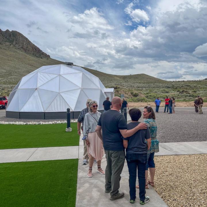 Community members mingling around the 33' Growing Dome greenhouse outside the wellness center