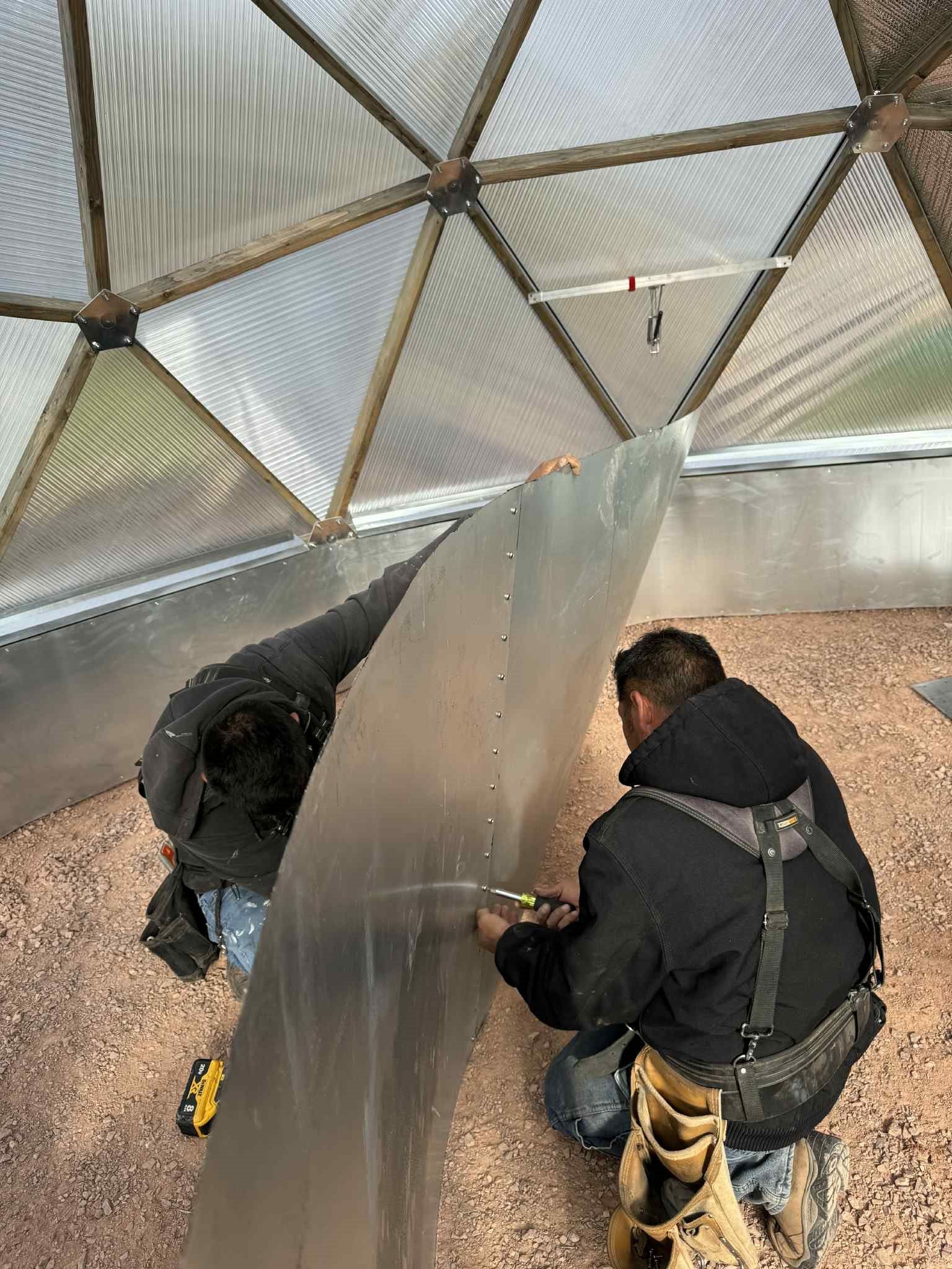 people working with a sheet of metal during dome construction