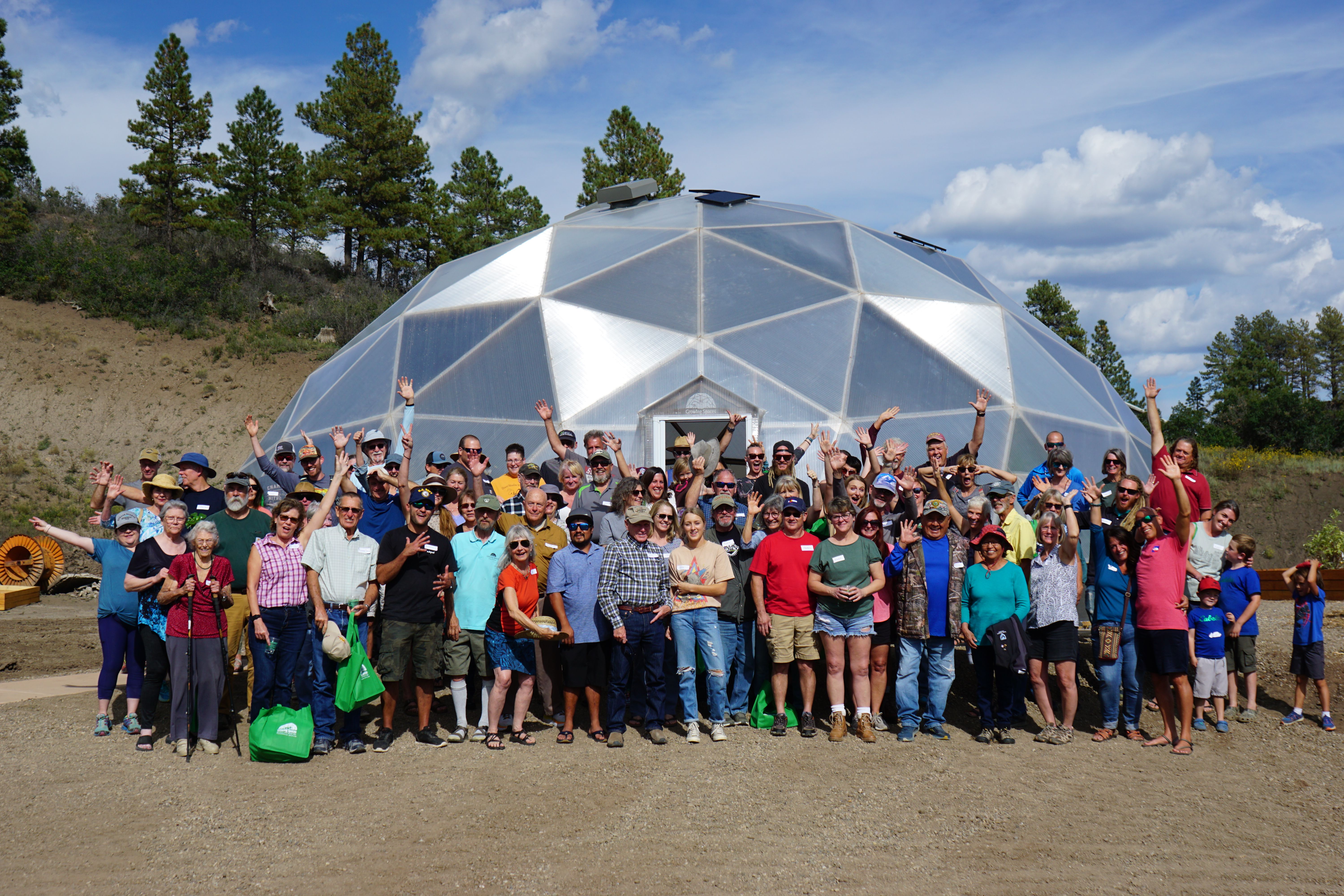 happy group portrait of growing dome enthusiasts in front of a geodesic dome greenhouse